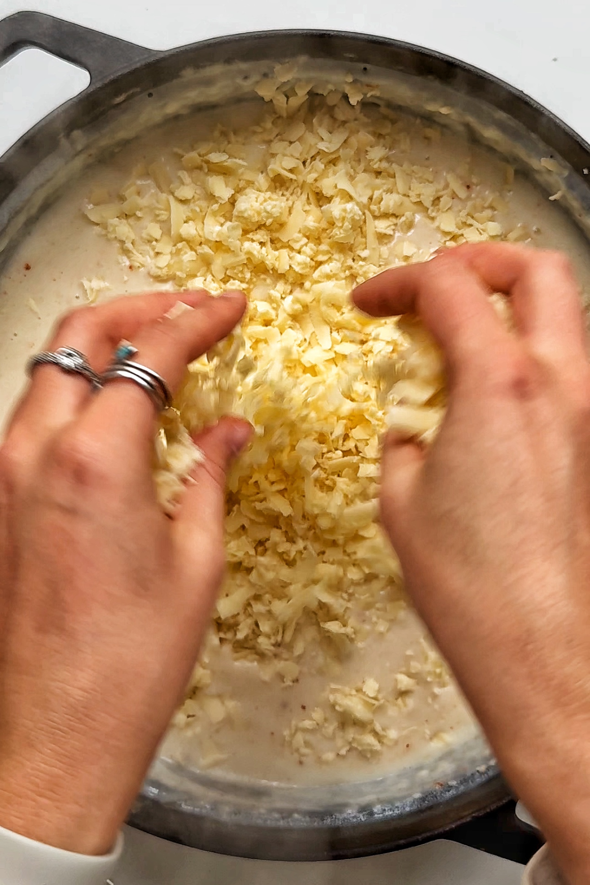 Adding mozzarella and cheddar cheese into our macaroni cheese sauce.