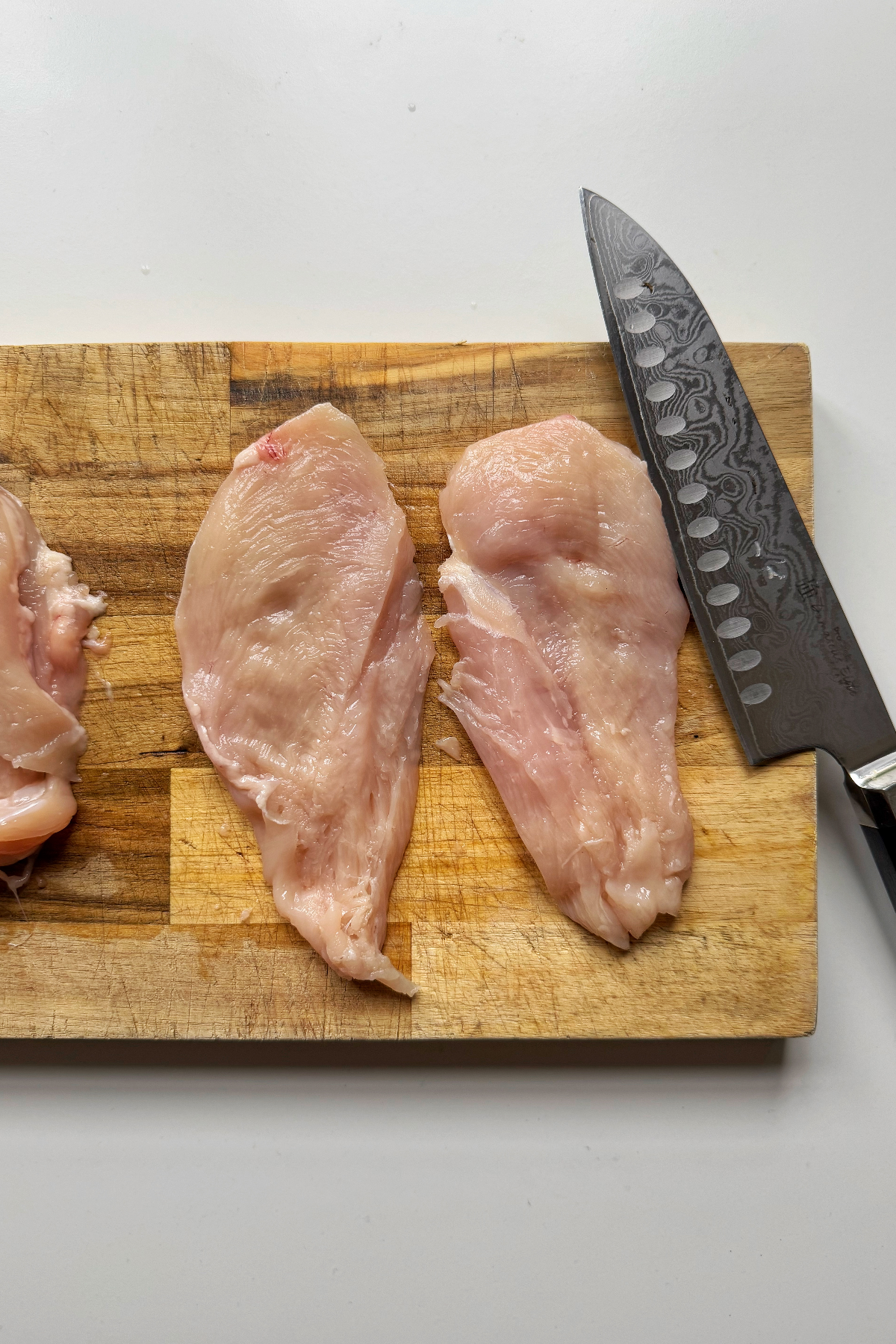 Slicing chicken breast in half.
