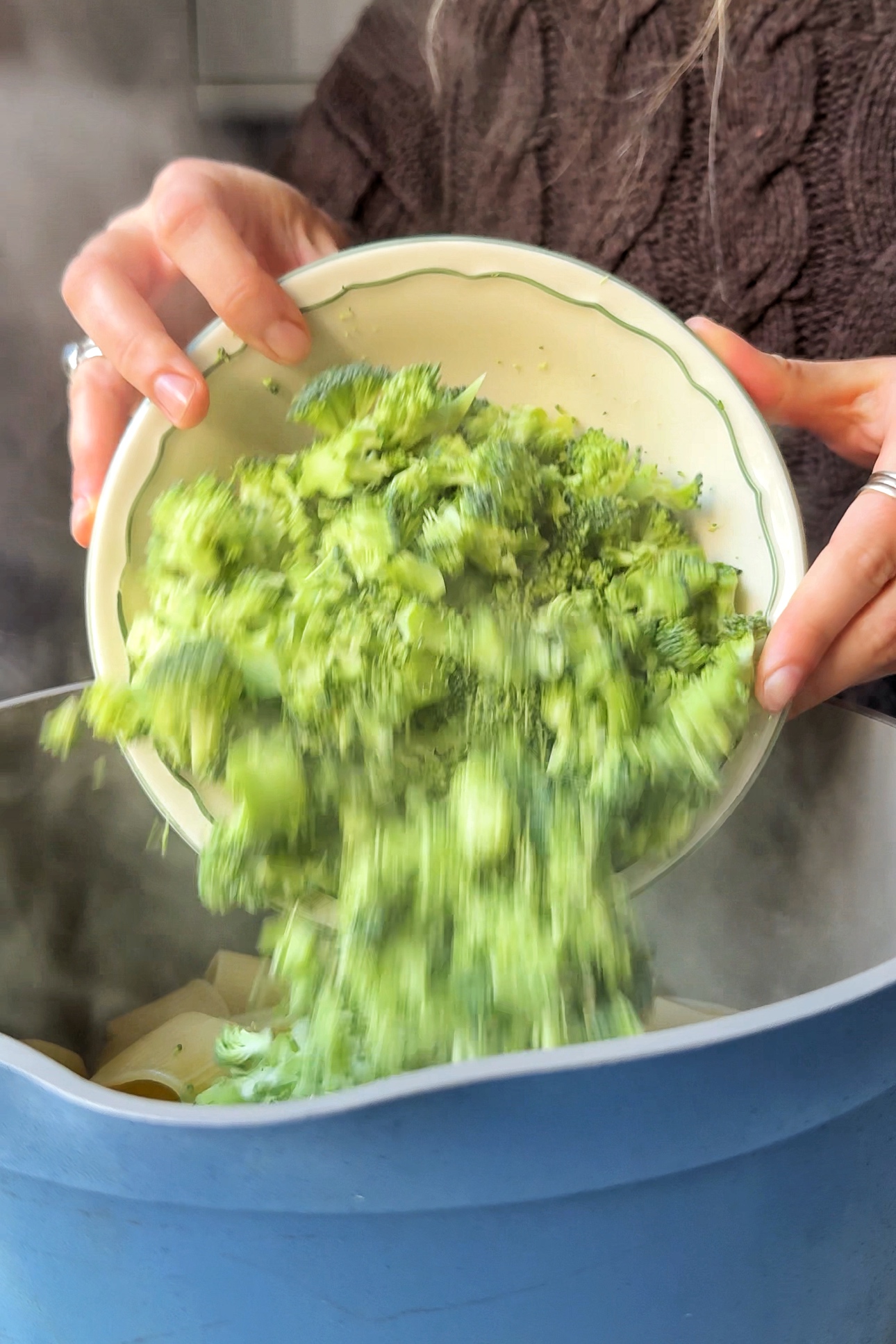 Pouring broccoli into the pasta pot.