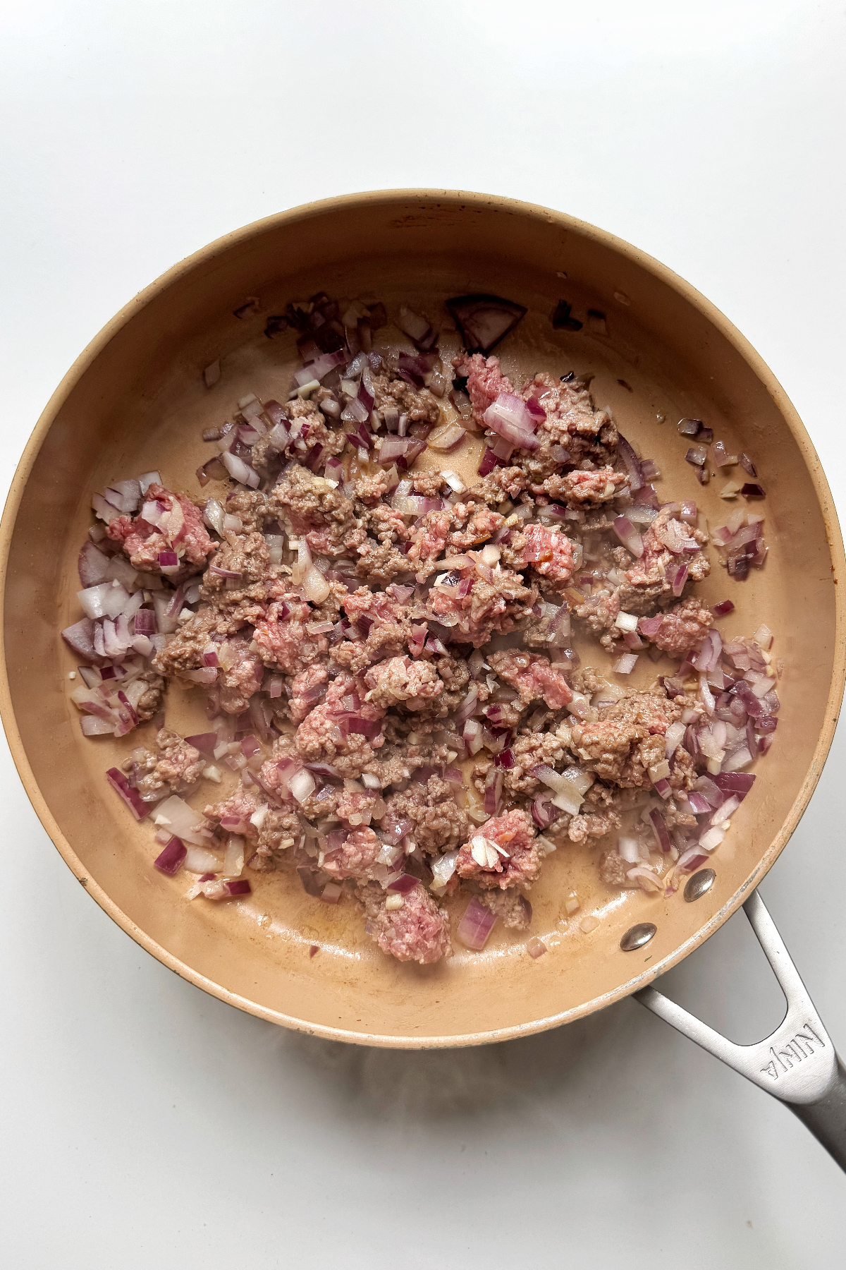 Frying ground turkey with red onion and garlic in a pan.