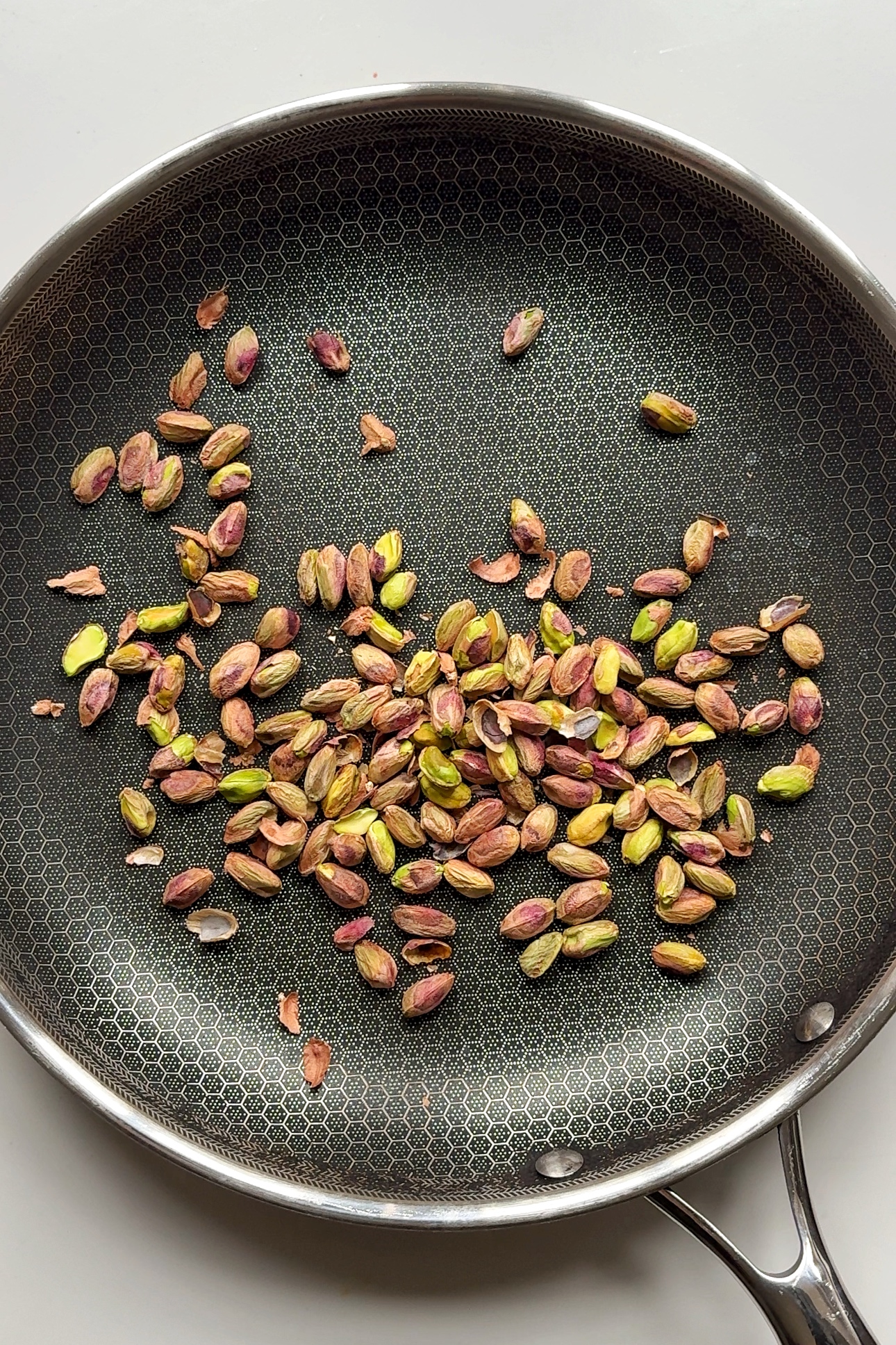 Toasting pistachios in metal pan.