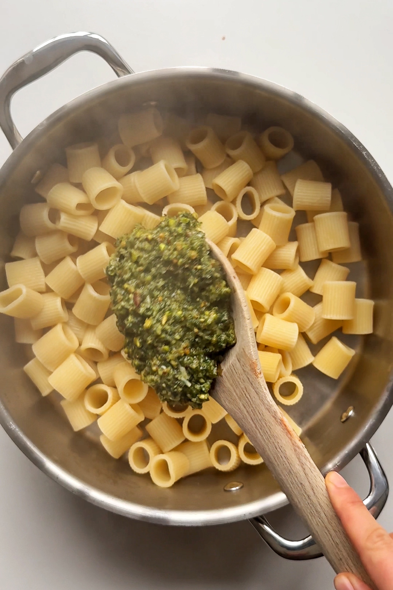 Combining pistachio pesto with pasta.