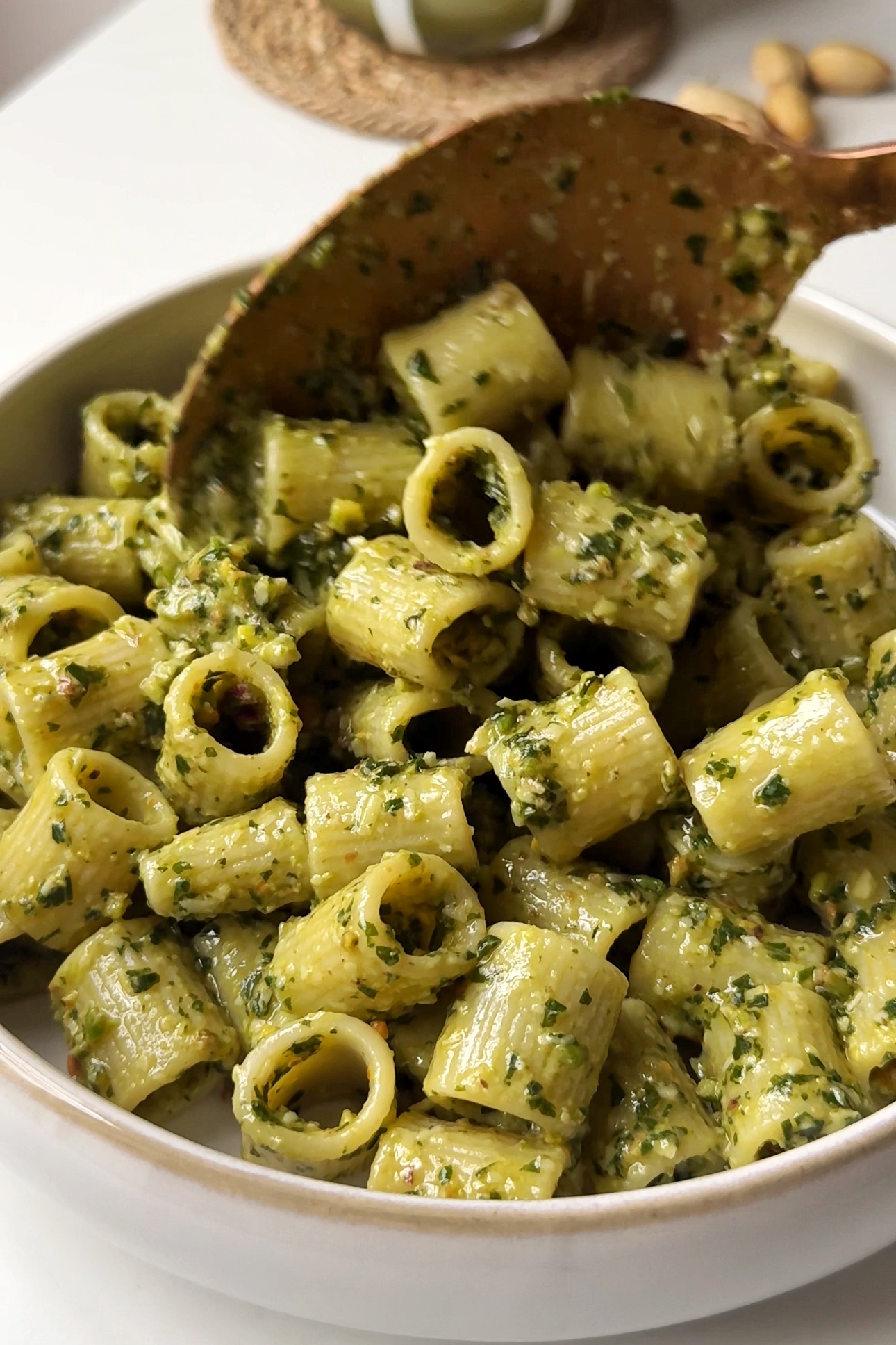 Plating up pistachio pesto with pasta in a bowl.