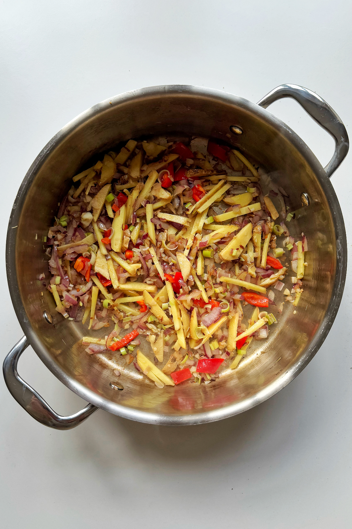 Frying ginger and chilli with garlic and onion in a metal pan.