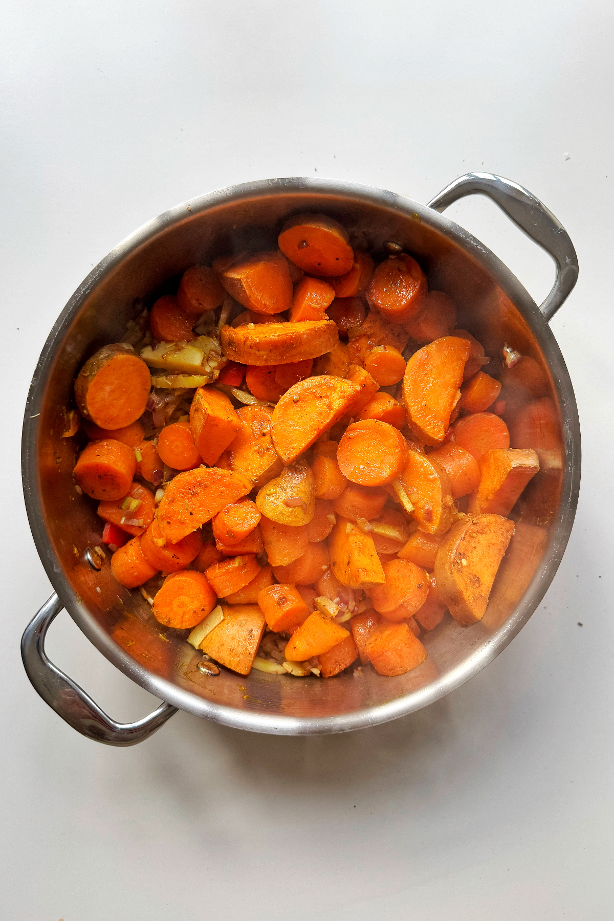 Adding the carrots and sweet potato to the pan.