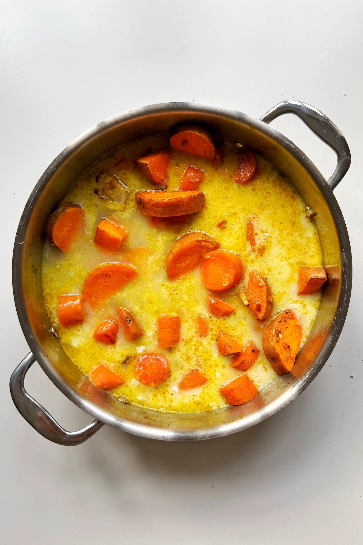 Adding coconut milk and water to the ginger carrot soup.