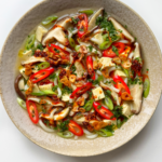 White bowl full of miso soup with mushrooms.