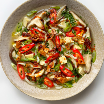 White bowl full of miso soup with mushrooms.