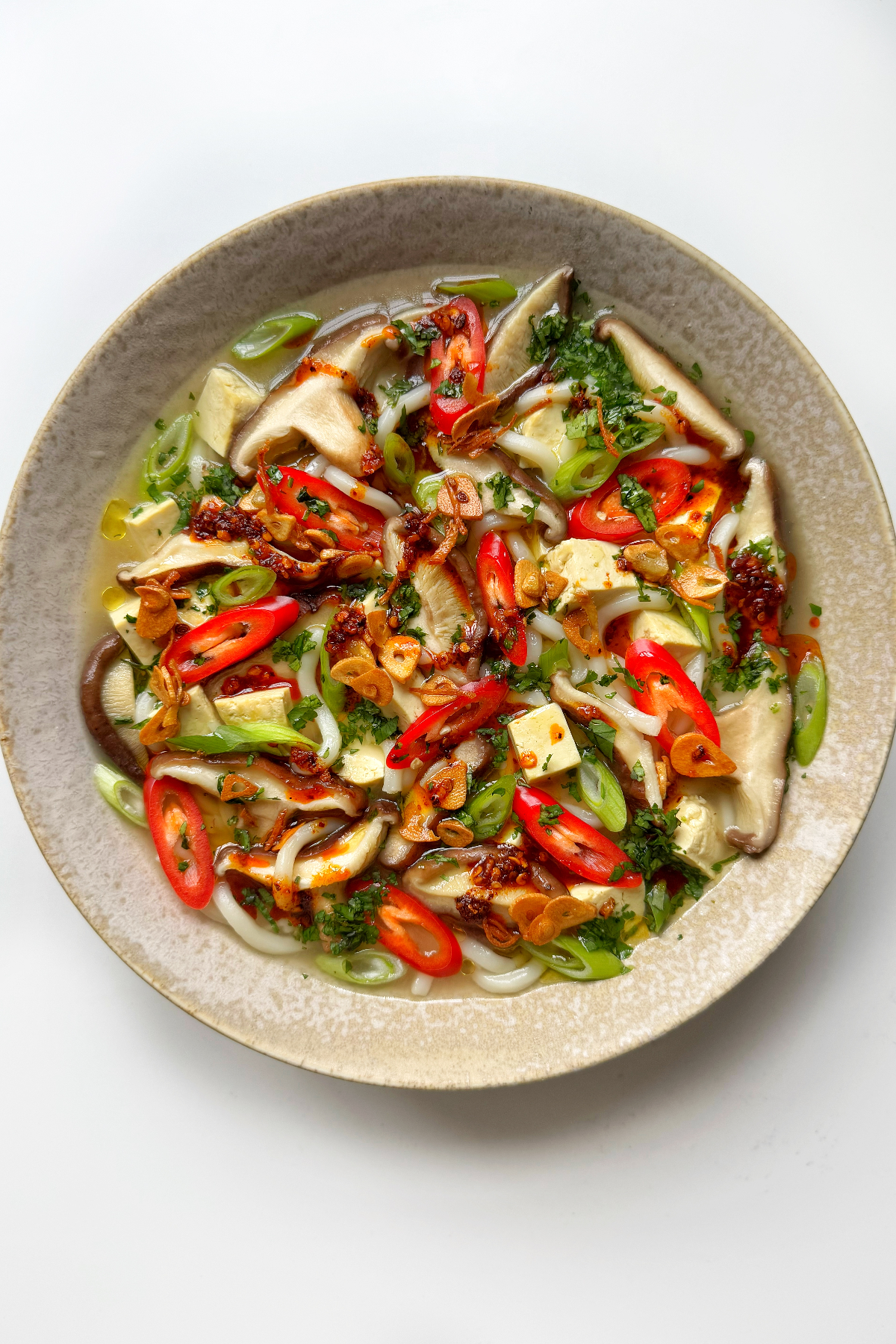 White bowl full of miso soup with mushrooms.
