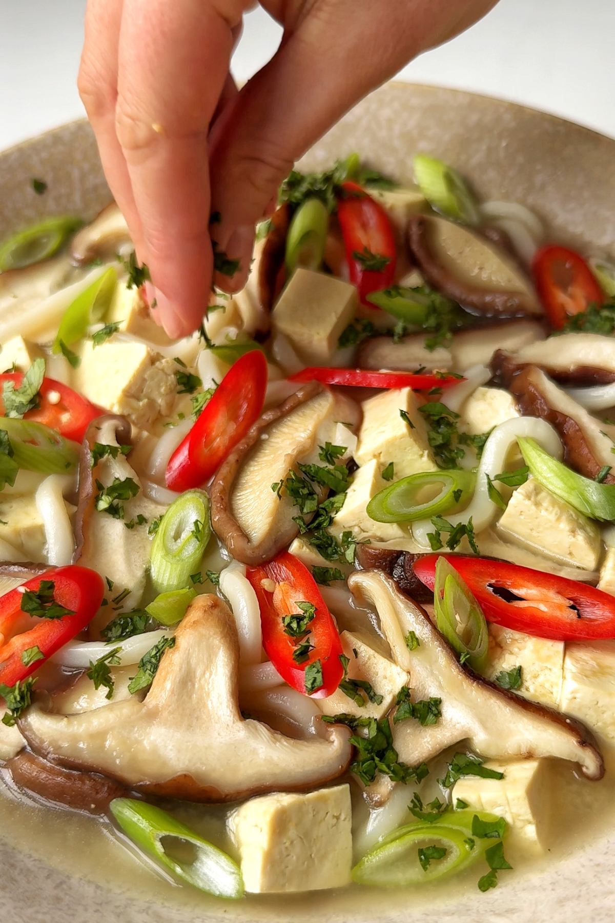 Plating up the miso soup with mushrooms topped with scallions, chilli flakes, and cilantro.