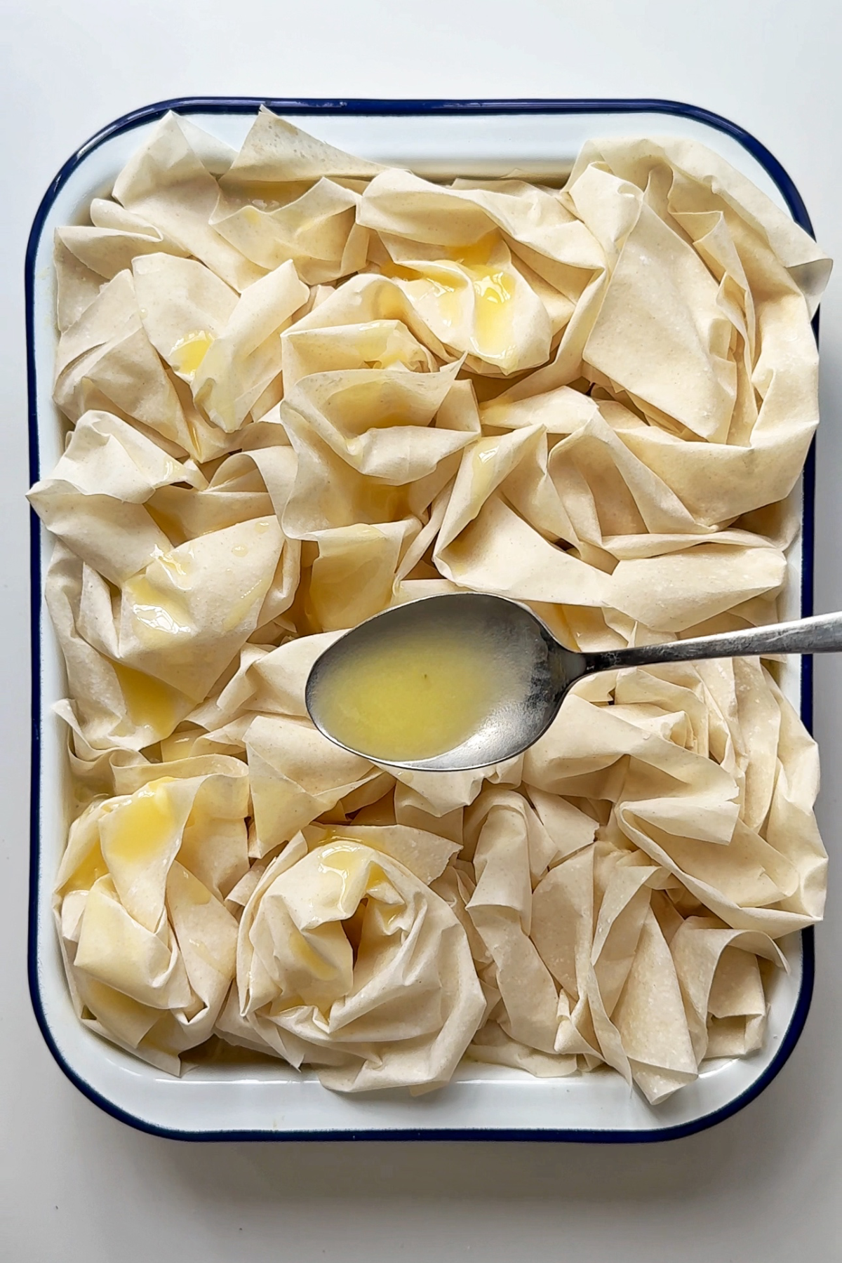 Covering the filo pastry with melted butter.
