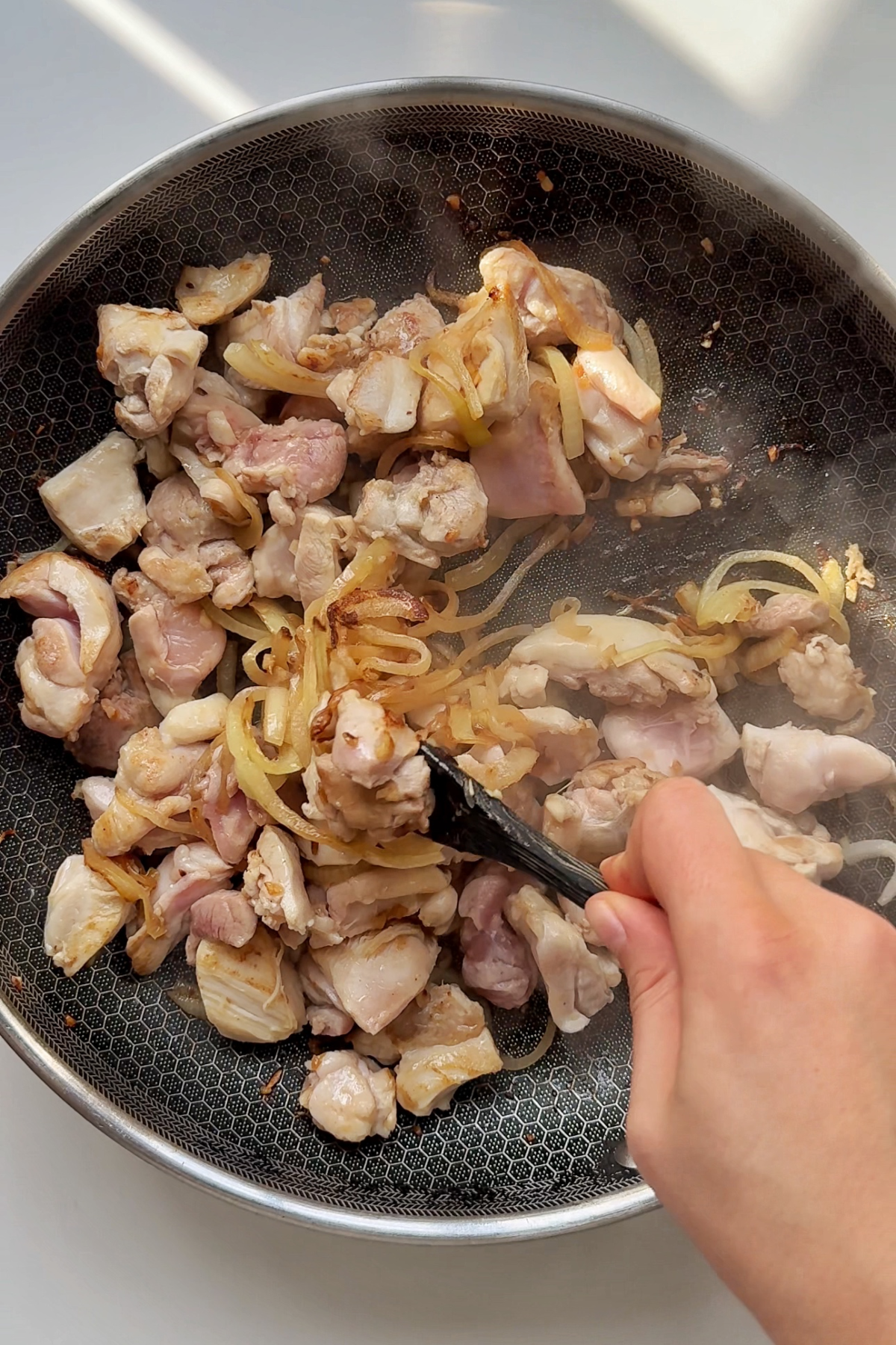 Frying garlic, onions, and chicken thighs in a pan.