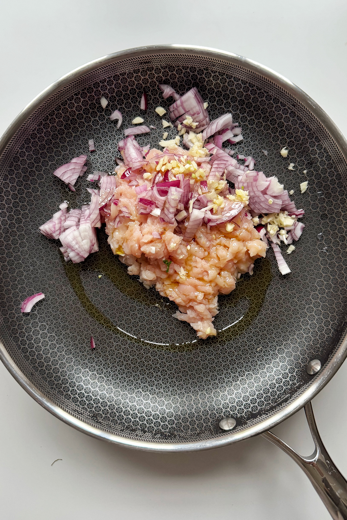 Frying ground chicken with red onion and garlic.
