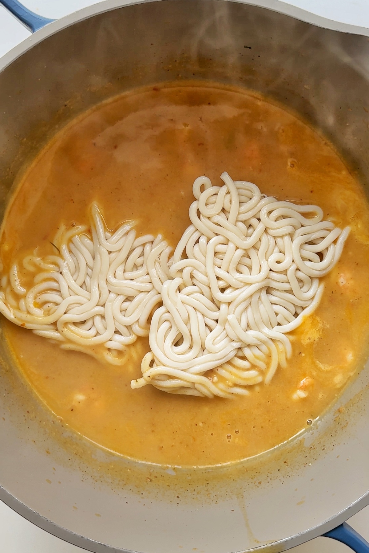 Adding udon noodles to shrimp broth.