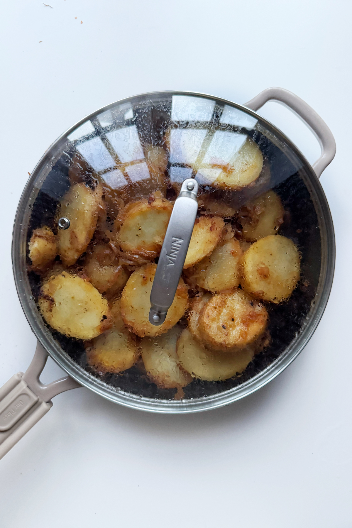 Adding the lid on the pan for skillet fried potatoes.