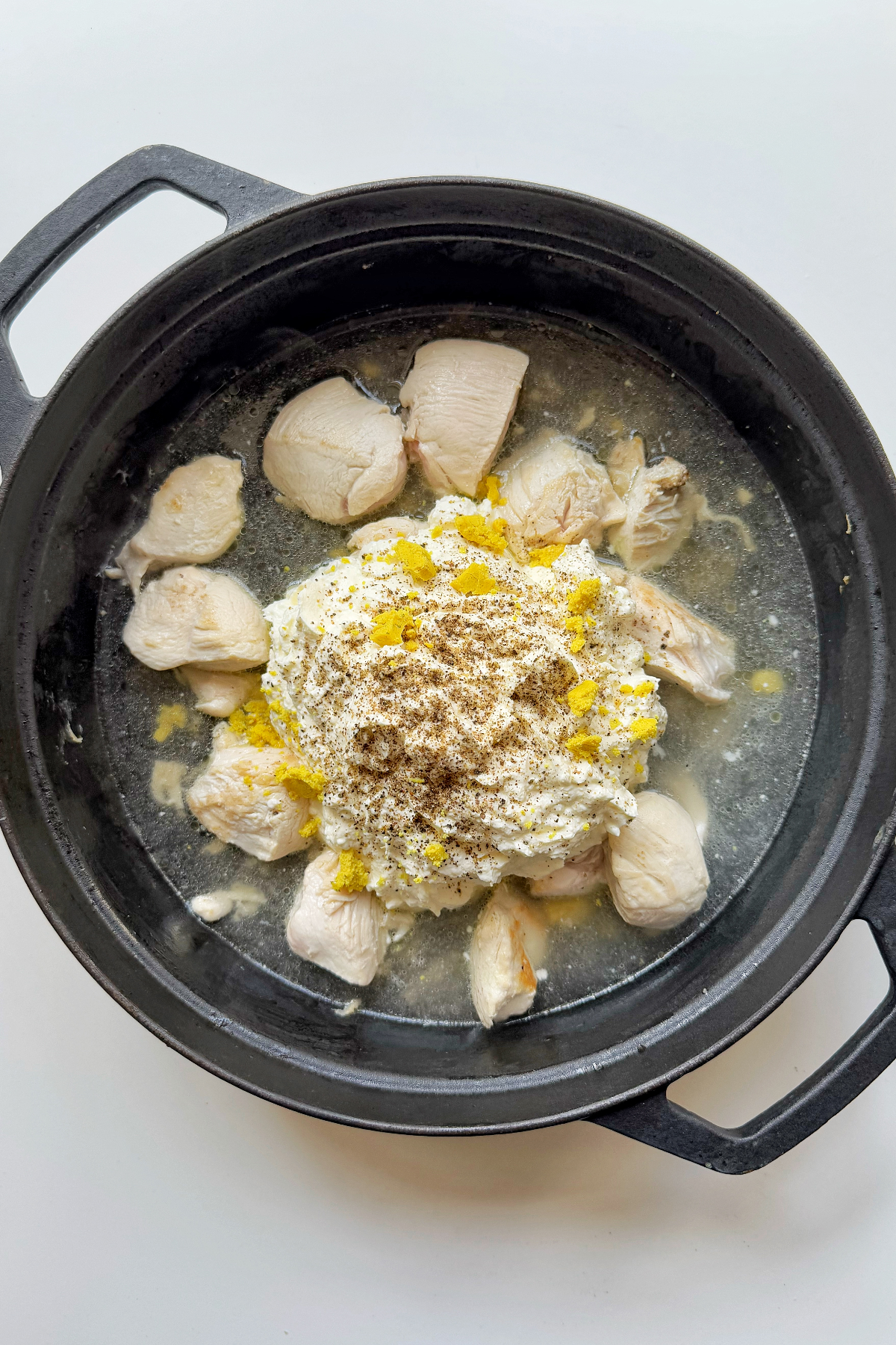 Combining the chicken with the cheesy sauce and lemon zest.