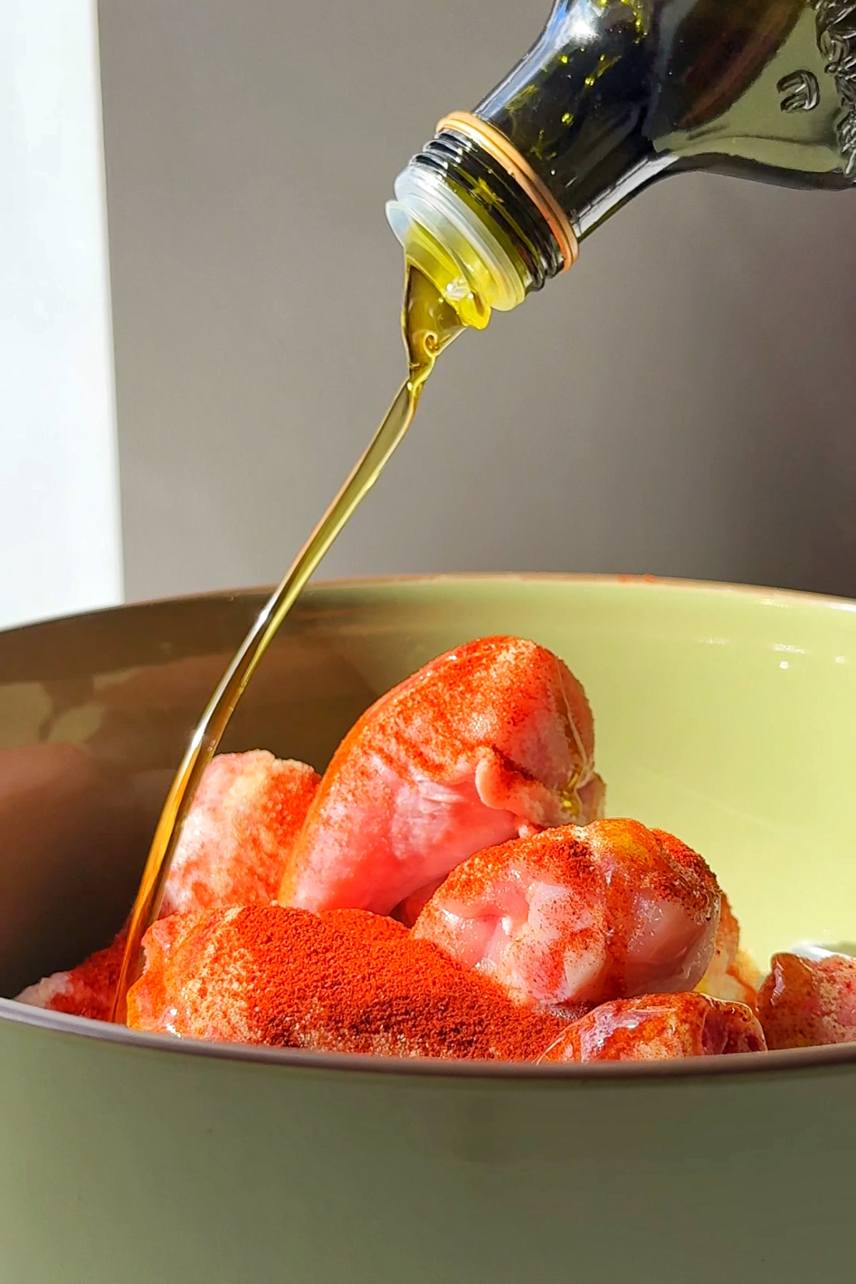 chicken drumsticks being drizzled with olive oil.