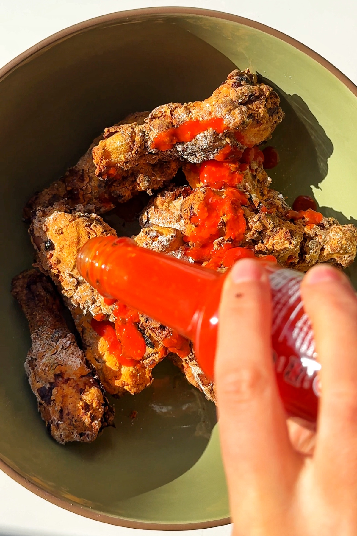Covering chicken drumsticks with hot sauce.