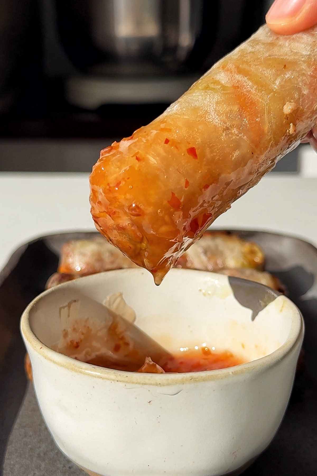 dipping air fryer summer rolls in sweet chilli sauce.