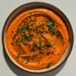 Roasted red pepper hummus on a plate.