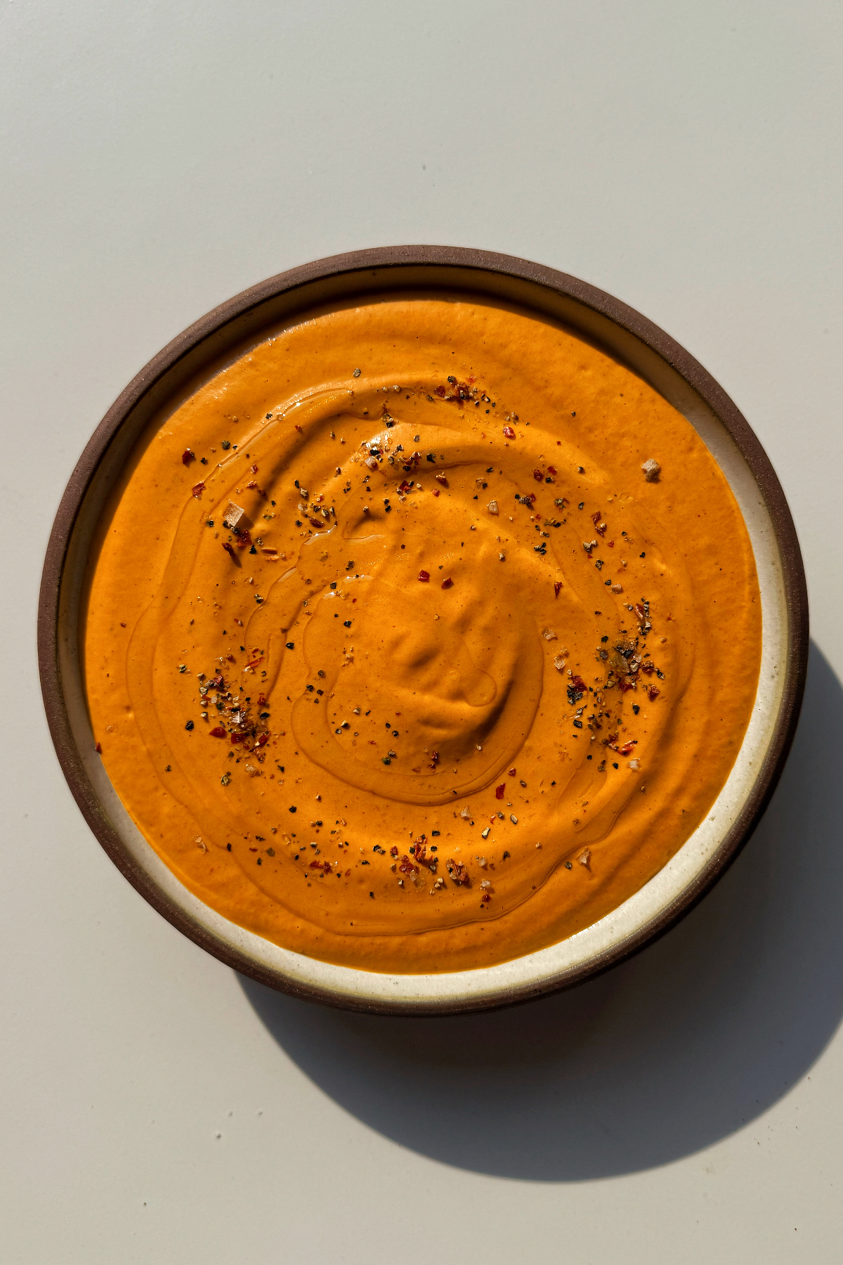 Roasted red pepper pasta sauce in brown bowl.