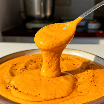 Spoonful of roasted red pepper pasta sauce in a bowl.
