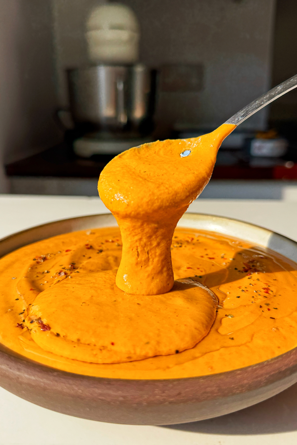 Spoonful of roasted red pepper pasta sauce in a bowl.