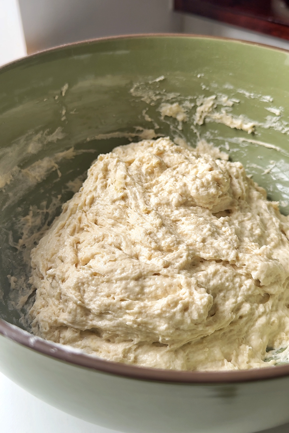 Making focaccia croissant dough in a green bowl.