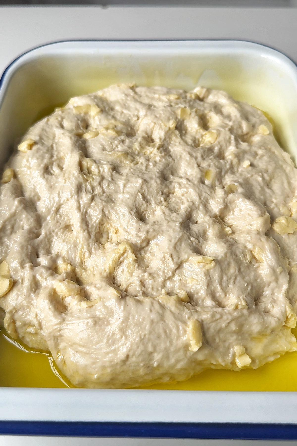 Focaccia croissant dough in metal tray with olive oil.