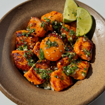 Avocado rice bowl with salmon bites and lime wedges.