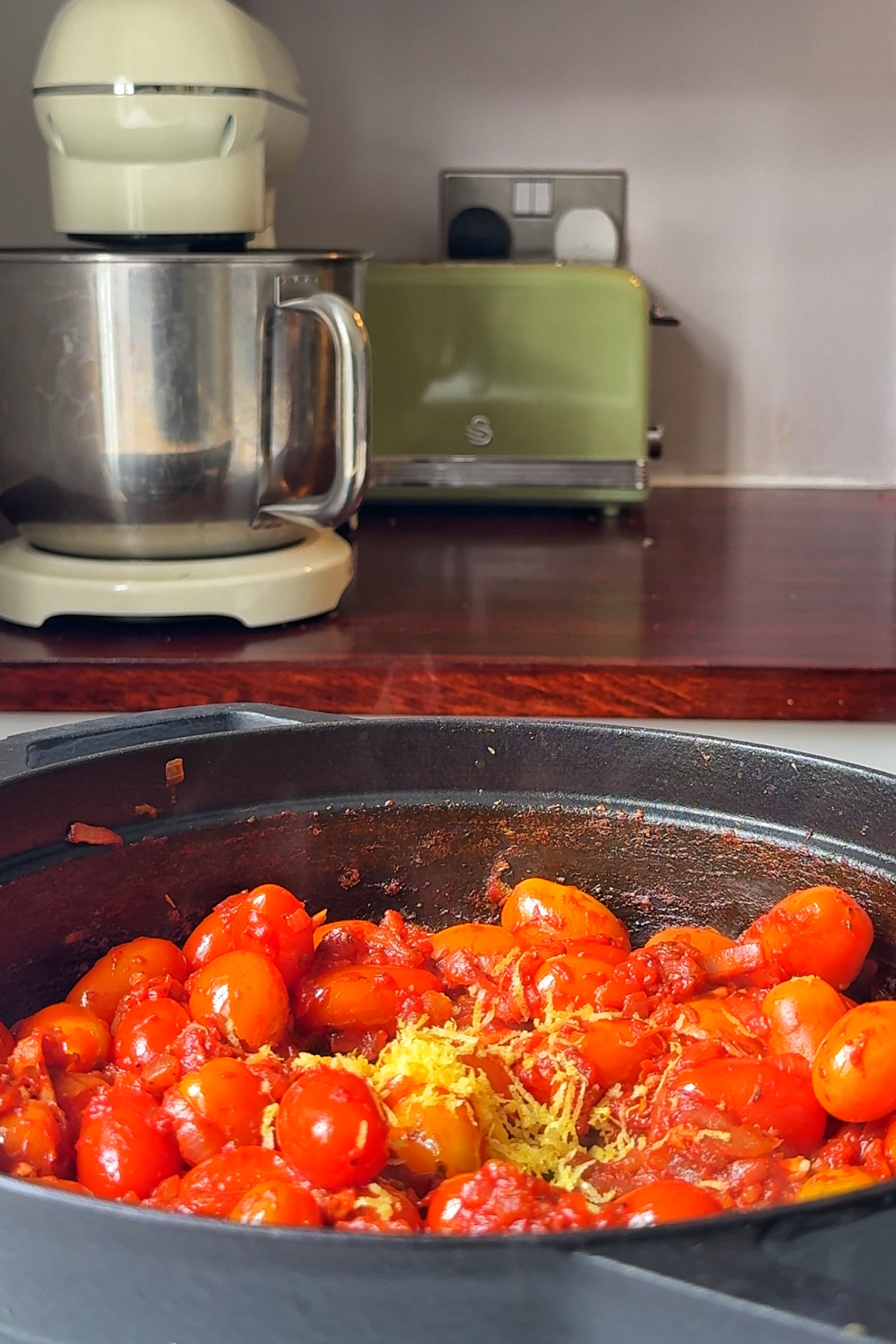 Frying tomatoes with lemon zest and seasonings in a pan.