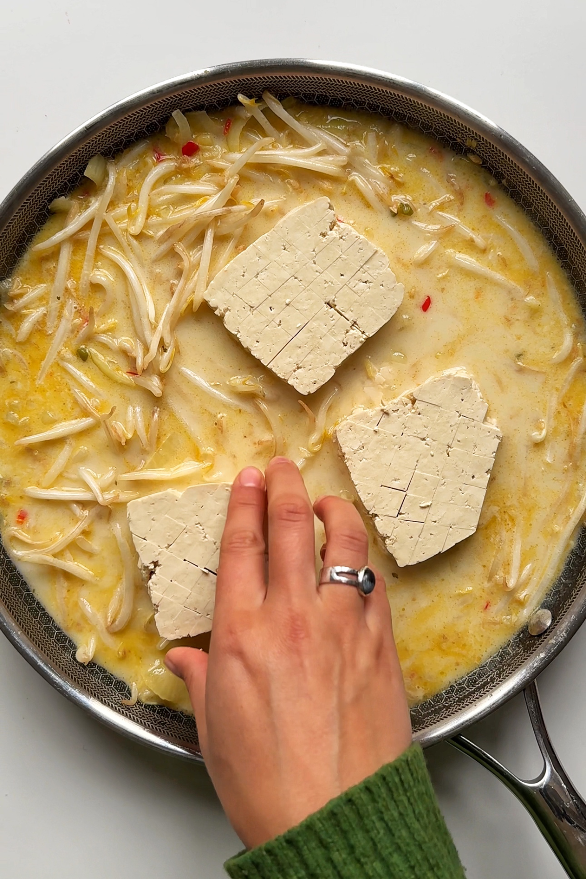 Adding the extra firm tofu into the spicy coconut sauce.