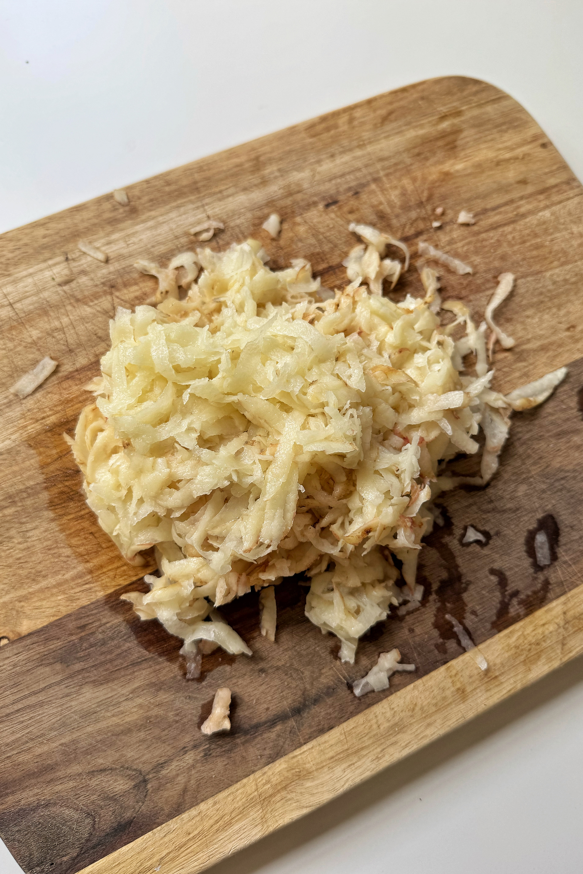 Grated potato on chopping board.