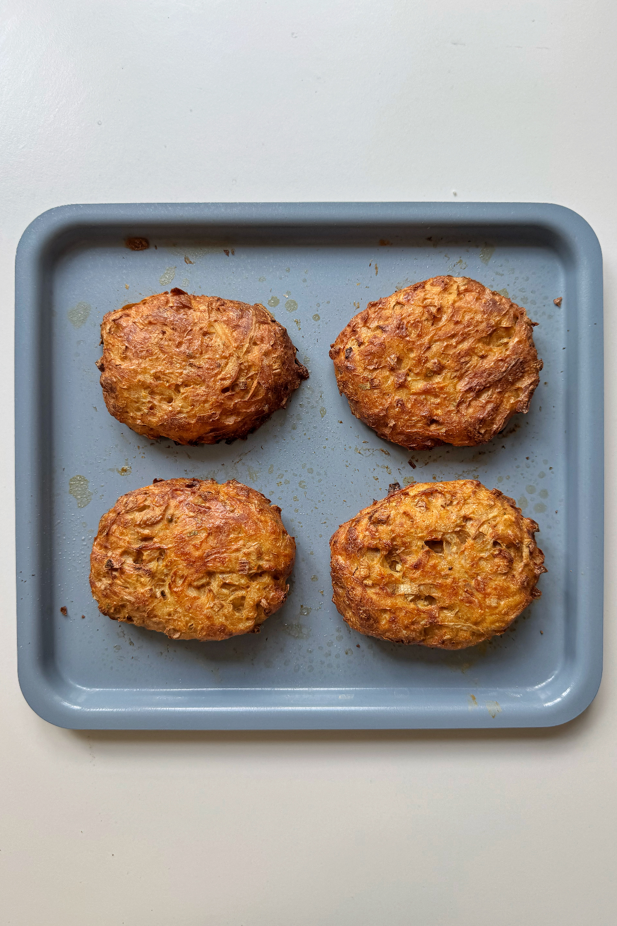 Cooked air fryer hash browns on blue tray.