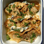 Crespelle in baking dish topped with dill and parsley.