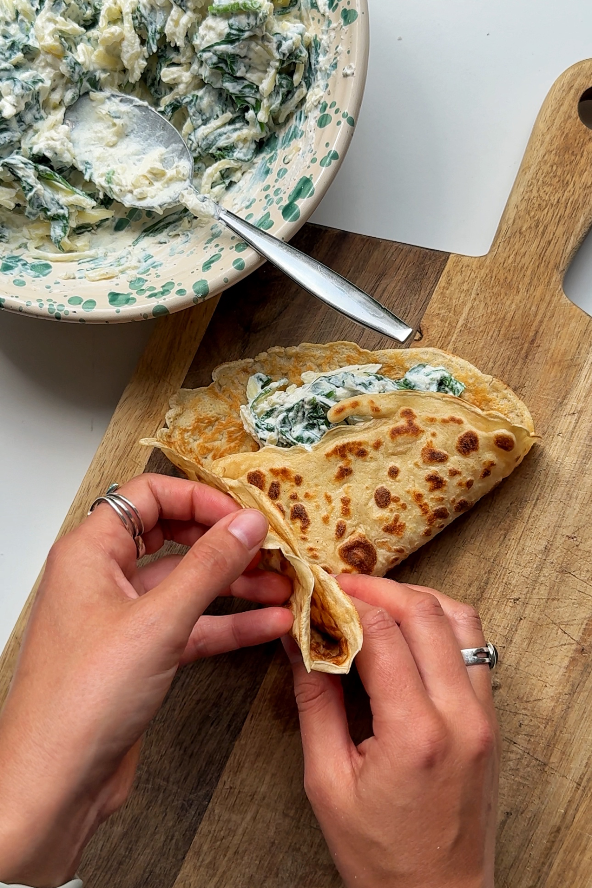 Folding the pancake into quarters with the spinach ricotta filling inside.