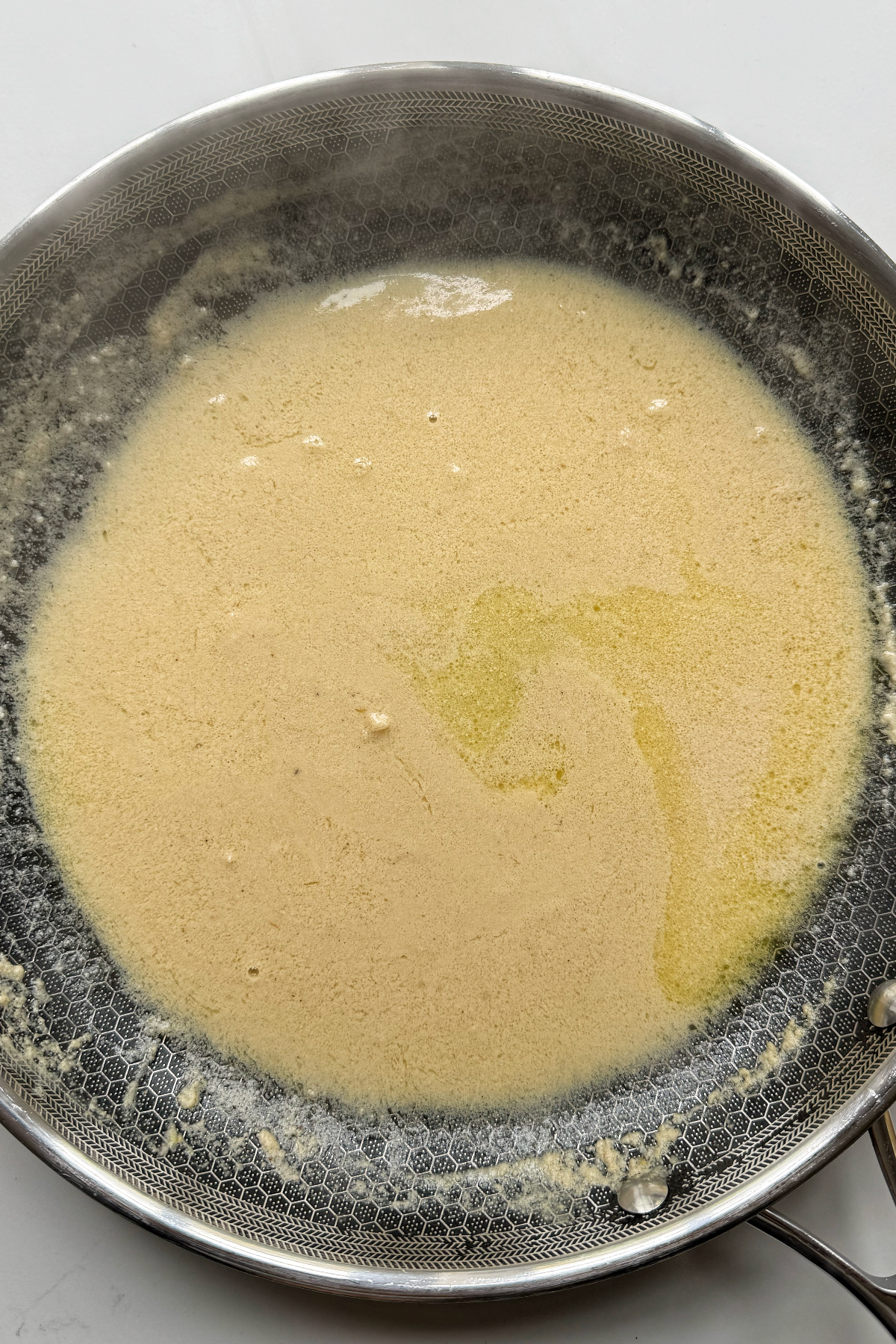Adding the tahini pasta sauce to the frying pan with garlic.