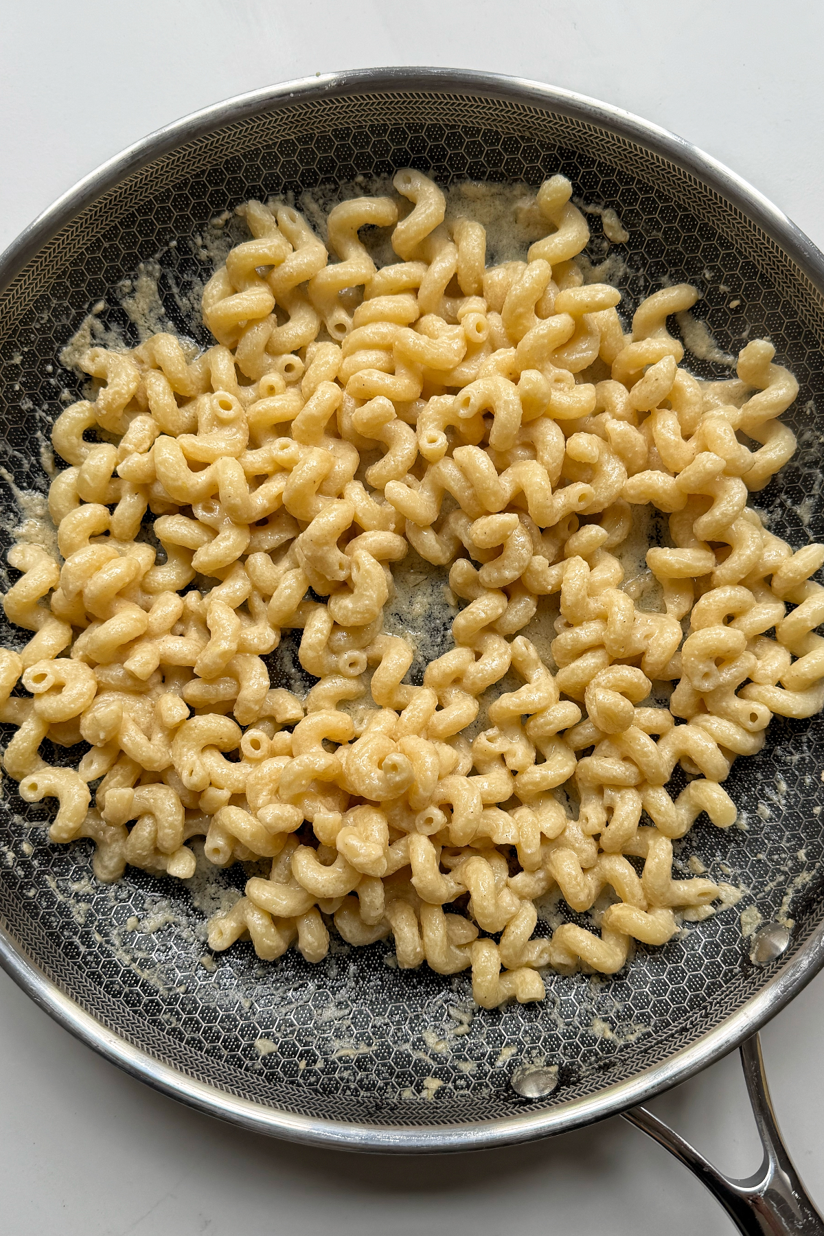 Combining pasta with tahini sauce.