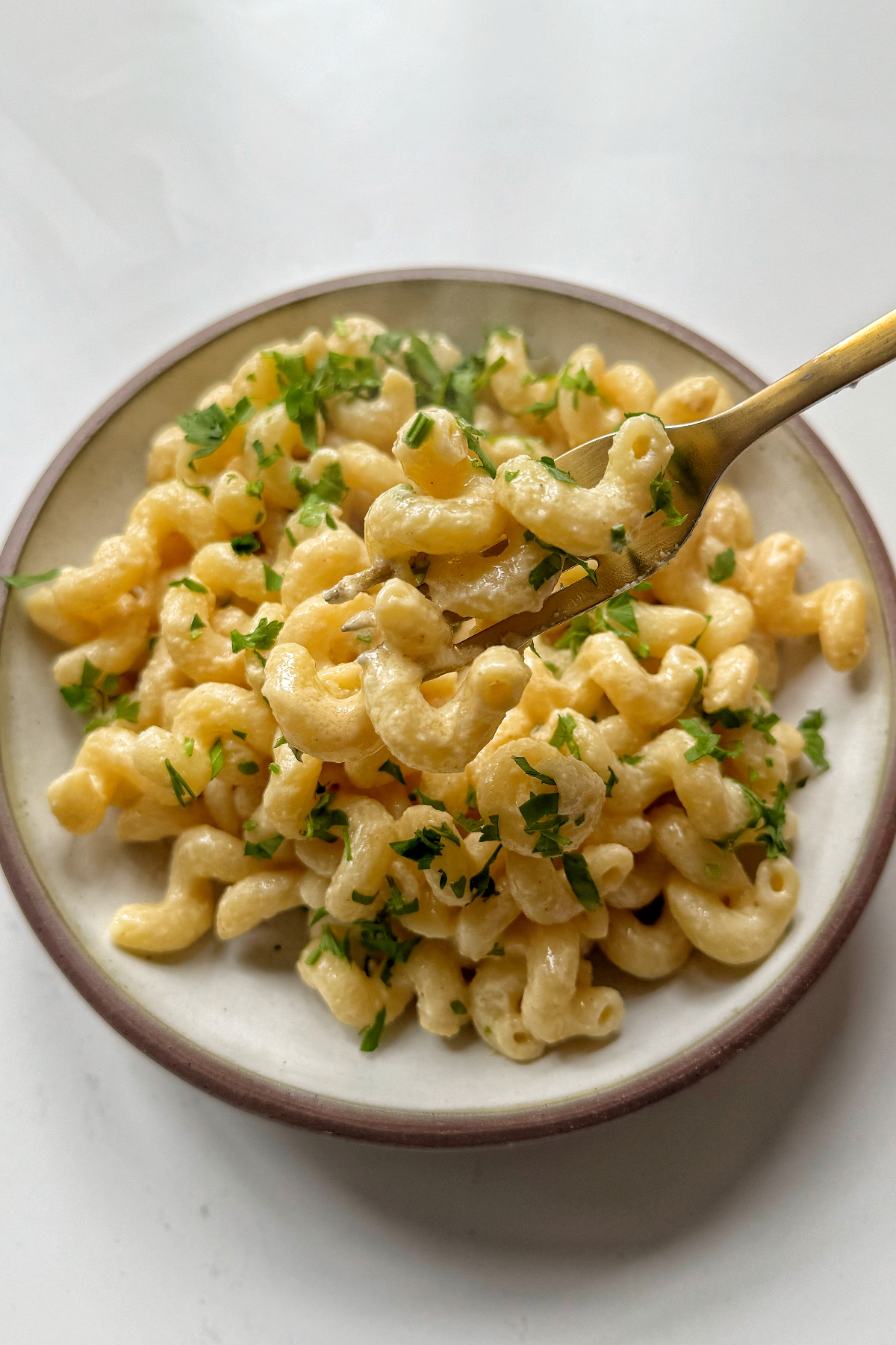 Tahini pasta in bowl garnished with parsley.