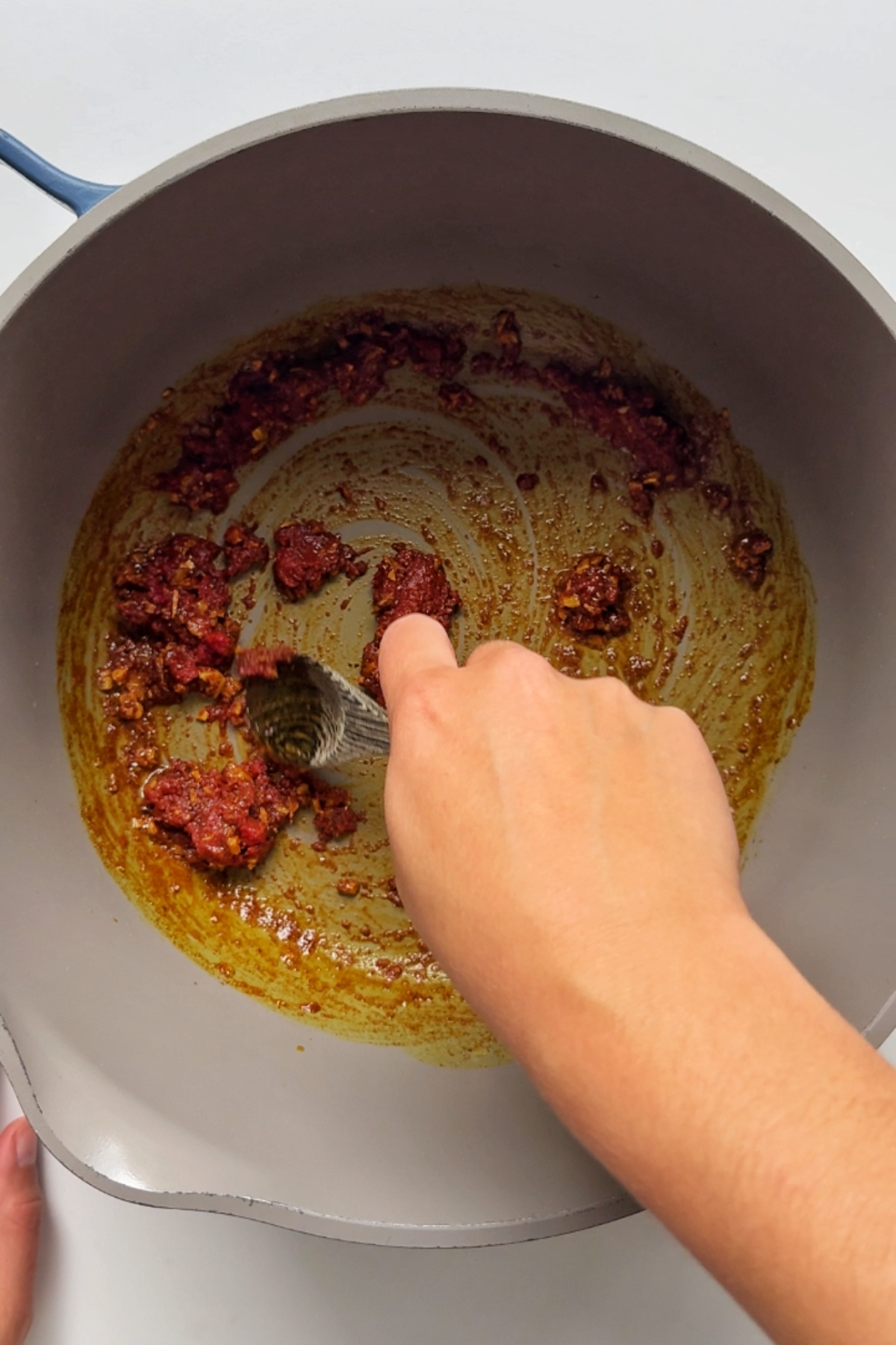Frying tomato paste in spices and oil.