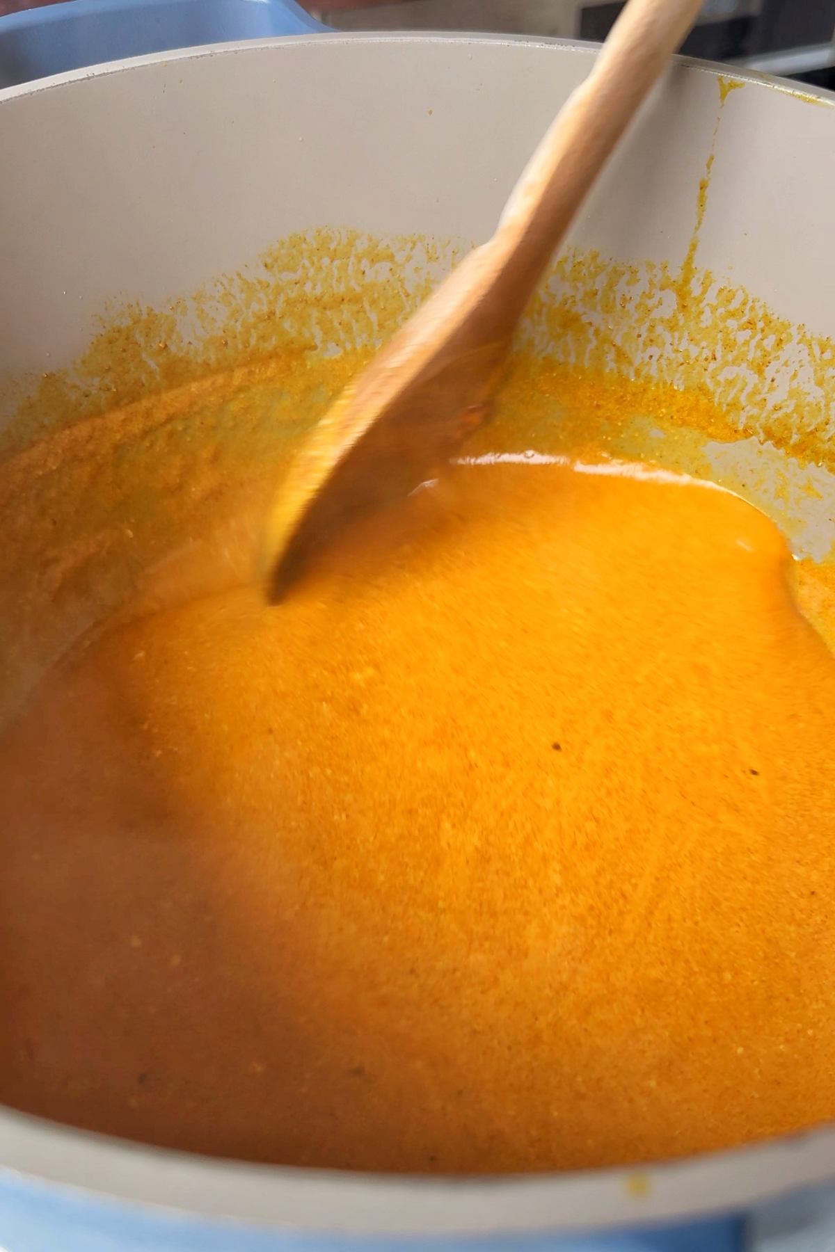 Creamy coconut milk sauce stirred in pan.