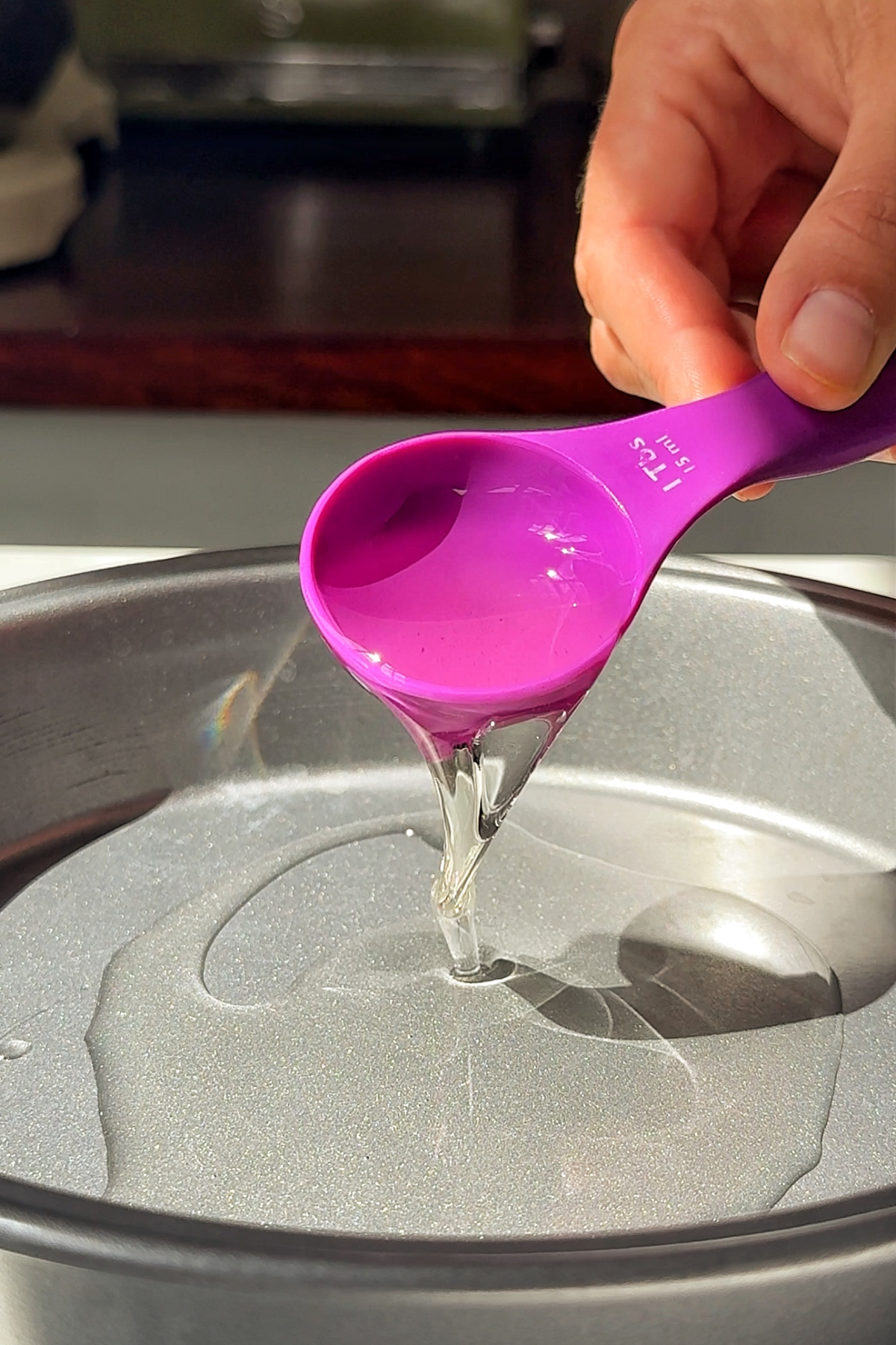 Pouring vegetable oil into a cake tin.