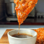 Kimchijeon slice dipped in sauce.