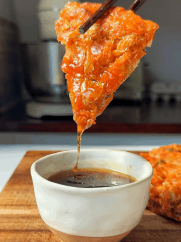 Kimchijeon slice dipped in sauce.