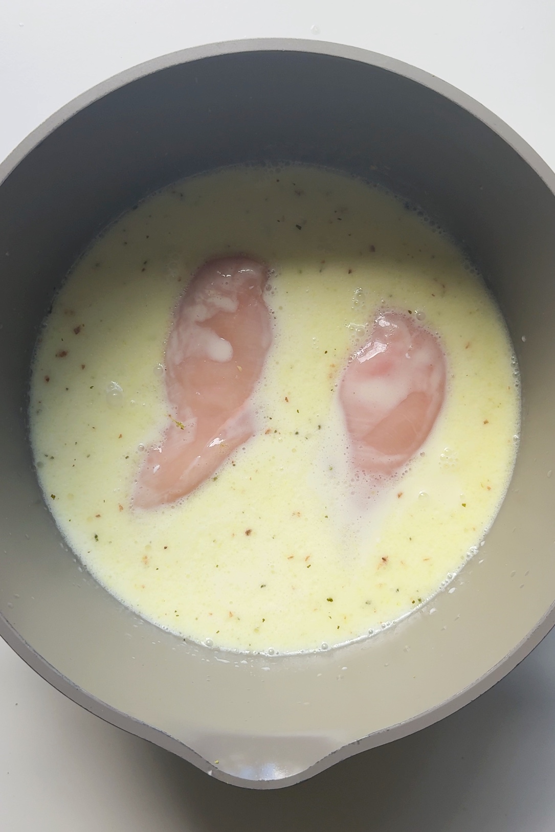Adding chicken into a lime and coconut sauce pan.