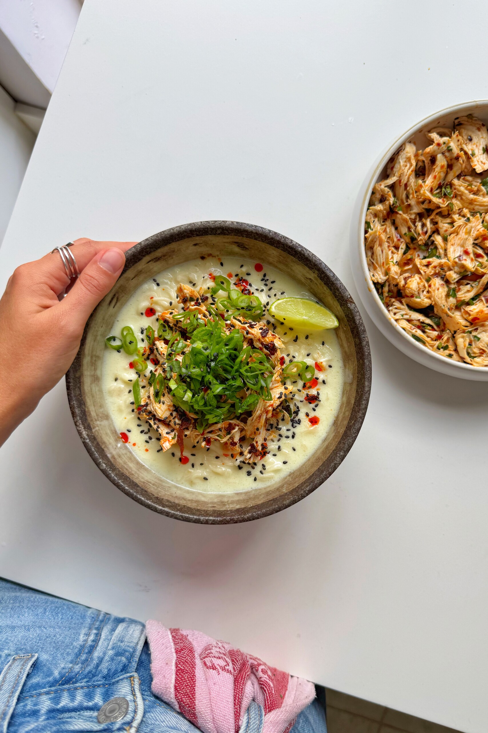 Bowl of noodles with plate of chili oil chicken.