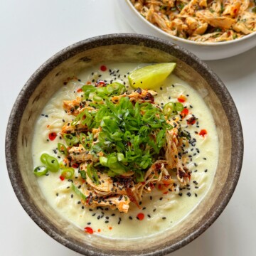 Lime and coconut chicken noodles in bowl on white surface.