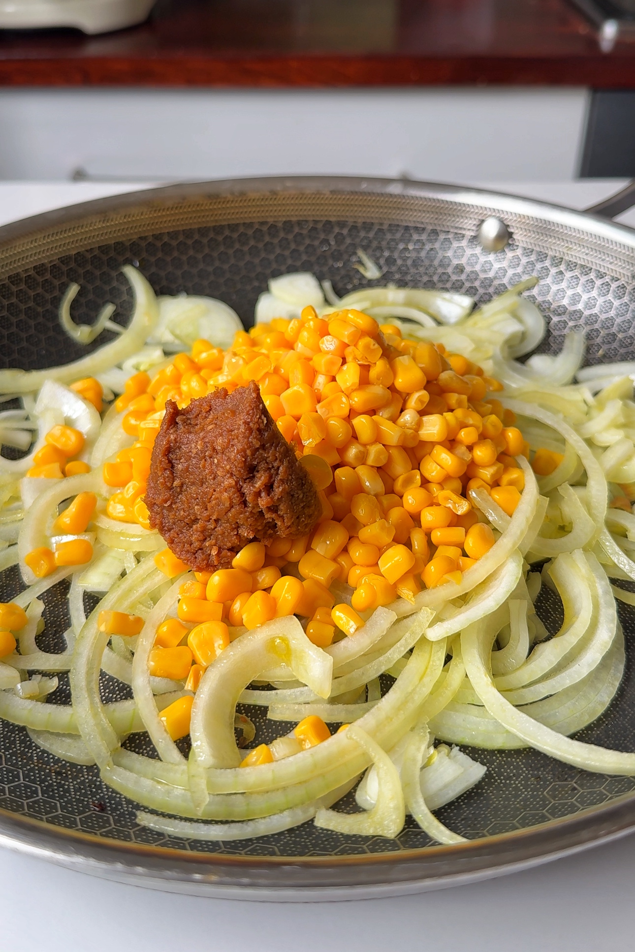 Frying onions, garlic, corn and miso paste in a pan.
