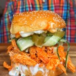 shredded buffalo chicken sandwich on wooden board.