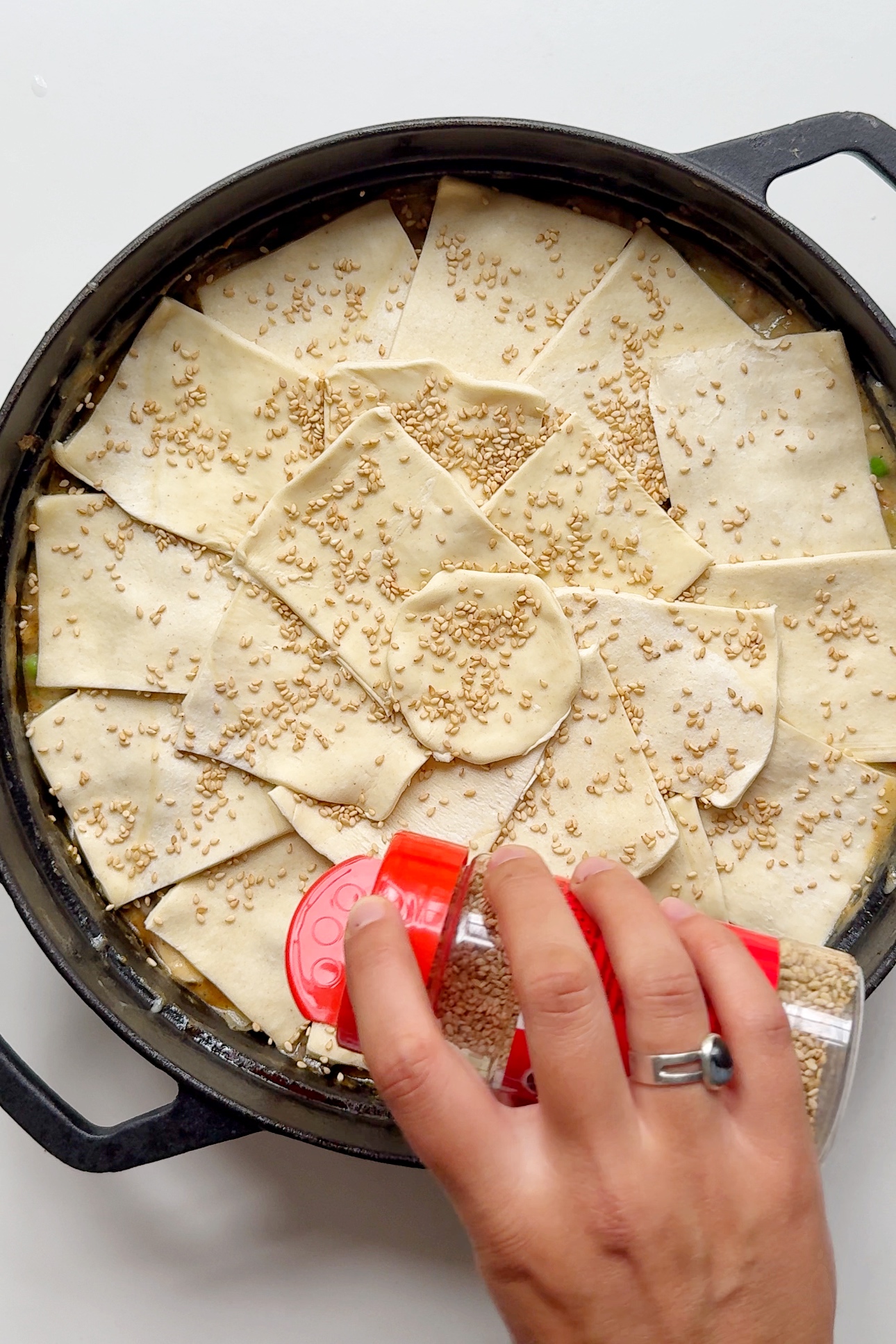 Adding sesame seeds onto chicken pot pie with cream of chicken soup.